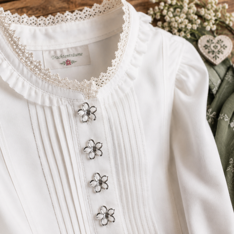 Silberfarbener Blumenknopf auf weißer Trachtenbluse mit Spitzenbesatz – dekorativer Ösenknopf für Dirndl, Trachtenmode und elegante Nähprojekte.